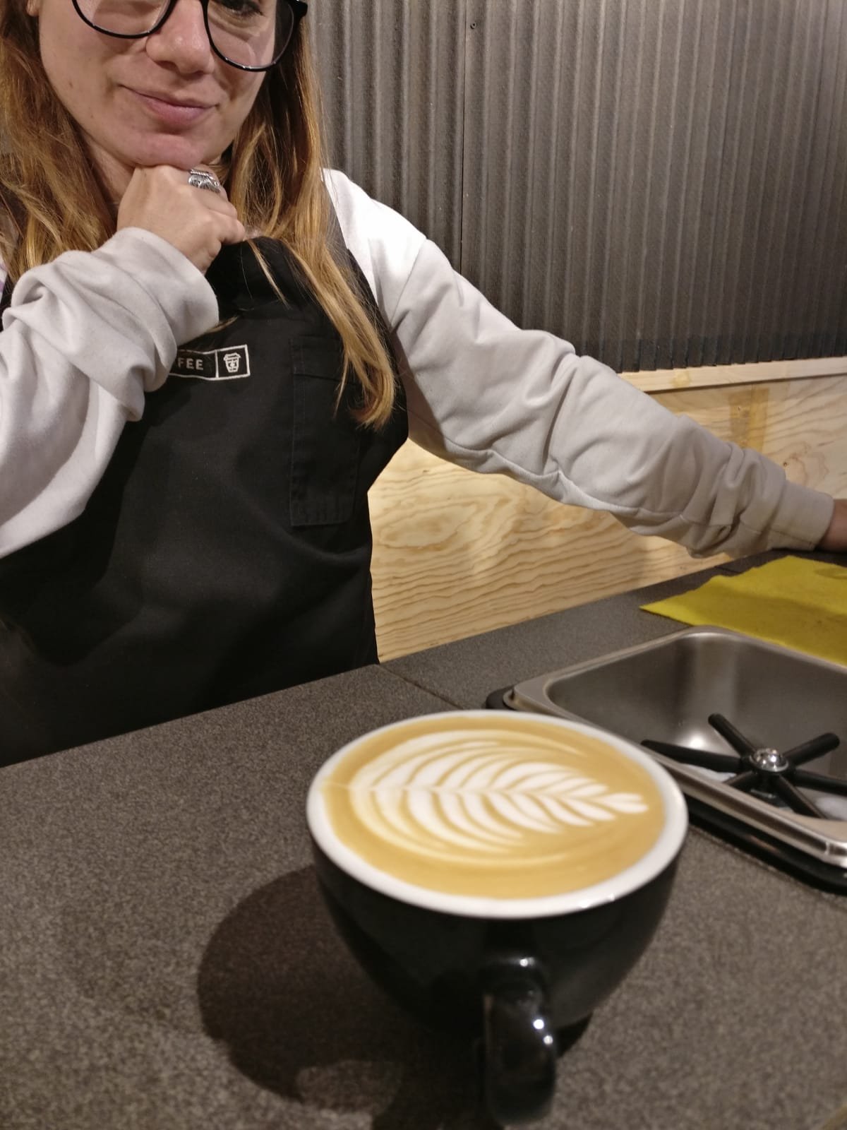 hipocresia del café de especialidad barista detrás de la barra y taza con latte art