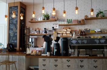 hipocresía del café de especialidad. Cafeteria con maquina de café y barra con estanterías al fondo y lamparas colgadas del techo Foto de Nafinia Putra en Unsplash