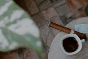 cafe cubano como resistencia taza pequeña de cafe en una mesa al lado de un puro y una hoja grande al lado vista desde arriba